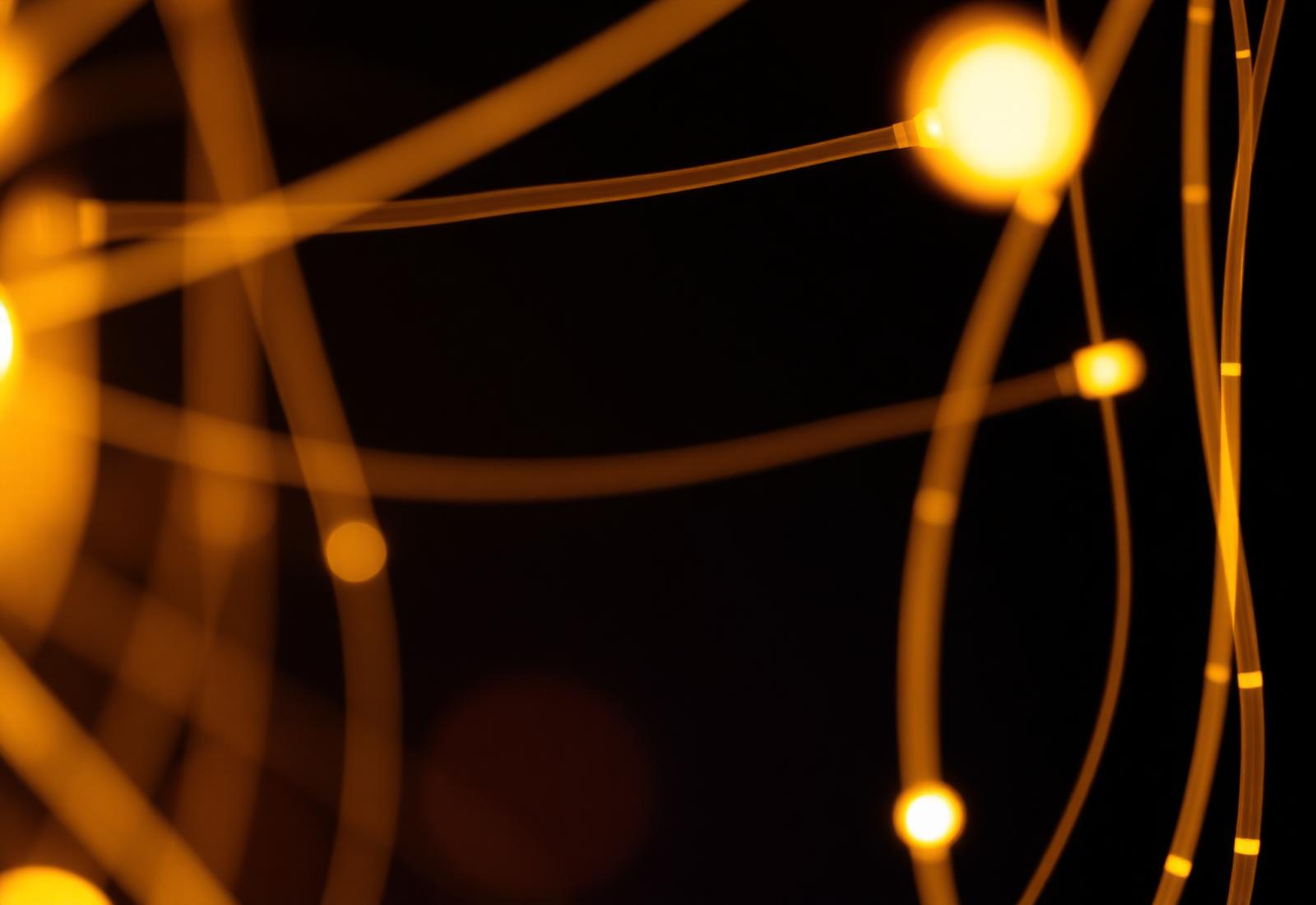 Fiber optic strands glowing warm amber on a midnight background